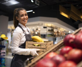 Supermarket worker supplying fruit department with food. Supermarket worker supplying fruit department with food.